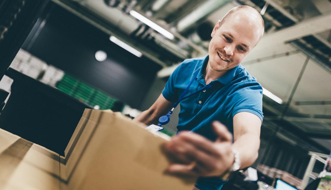 Logistiikkakeskuksen työntekijä käsittelee pahvilaatikoita.