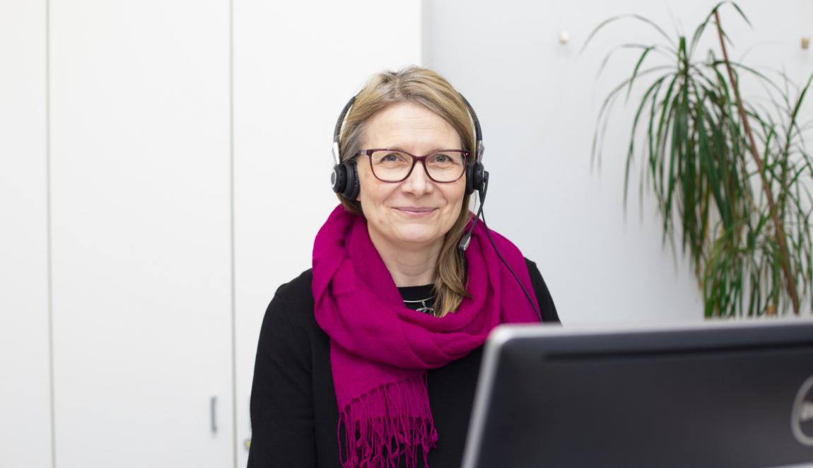 Myrkytystietokeskuksen farmaseutti Suvi Pajarre-Sorsa istuu tietokoneen ääressä kuulokkeet päässä.