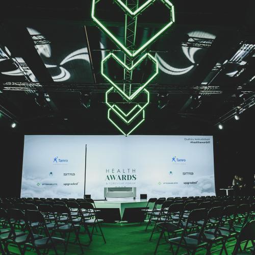 Foresight Forum -tapahtuman näyttämö kuvattuna salin takaosasta. Katossa isoja vihreitä valoputkista tehtyjä sydämiä.