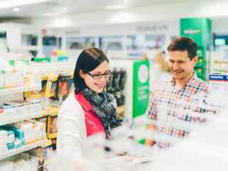 Tamron edustaja esittelee apteekissa tuotteita asiakkaalle.