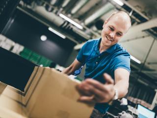 Logistiikkakeskuksen työntekijä käsittelee pahvilaatikoita.