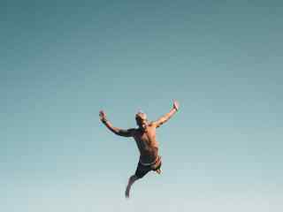 Nuorehko mies hyppää eteenpäin.