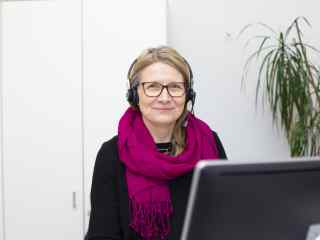 Myrkytystietokeskuksen farmaseutti Suvi Pajarre-Sorsa istuu tietokoneen ääressä kuulokkeet päässä.