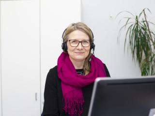 Myrkytystietokeskuksen farmaseutti Suvi Pajarre-Sorsa istuu tietokoneen ääressä kuulokkeet päässä.