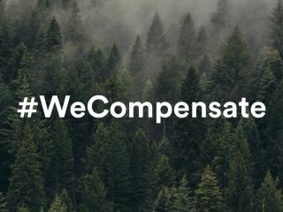 Kuva kuusimetsästä, jonka päällä teksti #WeCompensate.